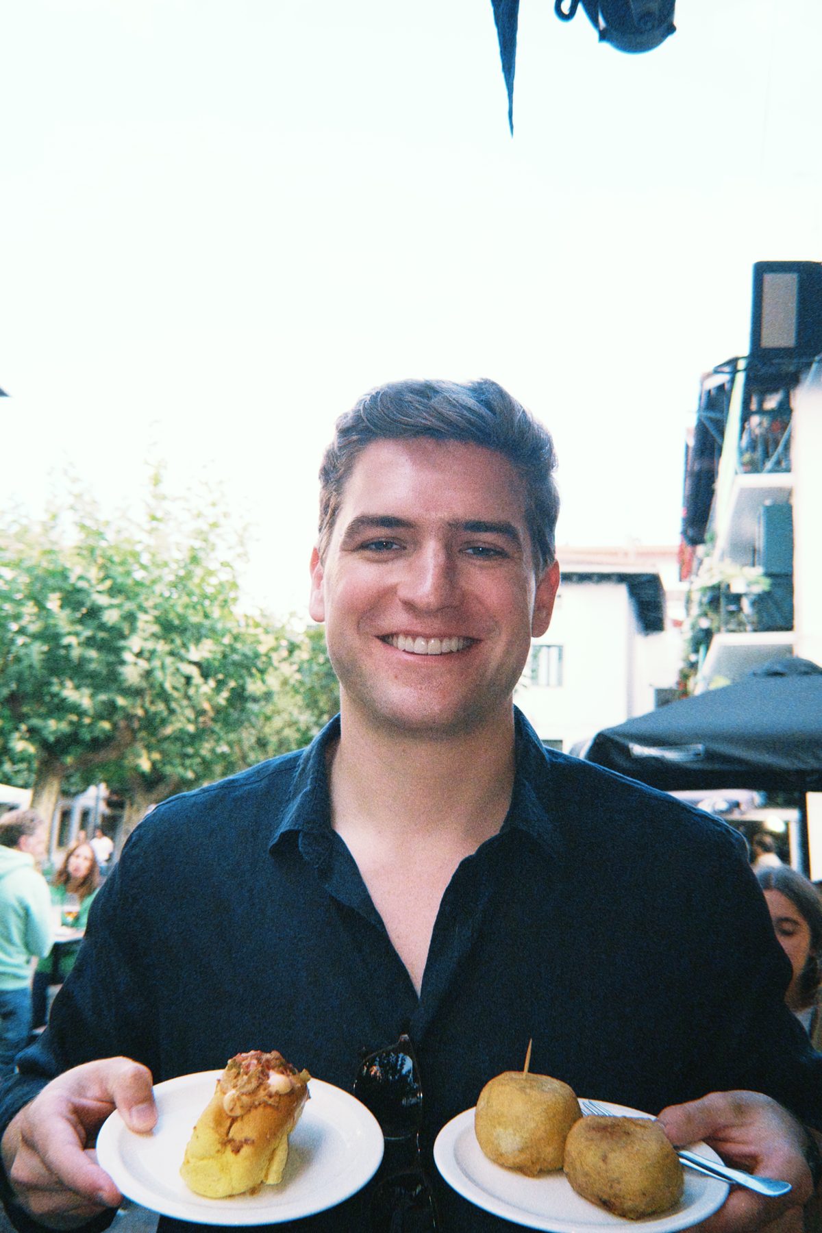 Roark Stockwell smiling and holding two plates of tapas